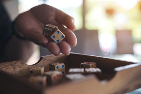Closeup image of hand holding and rolling wooden dices 