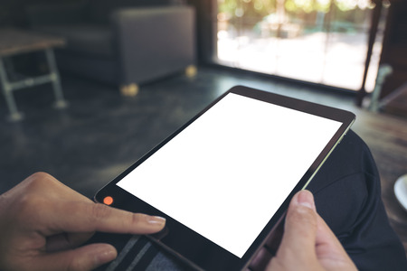 Mockup image of a woman sitting cross legged and holding black tablet pc with blank white desktop...