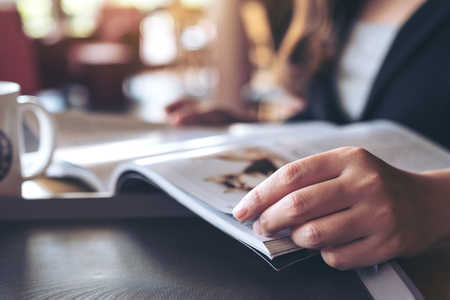 Closeup image of a business woman reading a book with coffee cup on table in cafe の写真素材