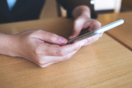 Closeup image of a woman holding , using and looking at smart phoneの写真素材