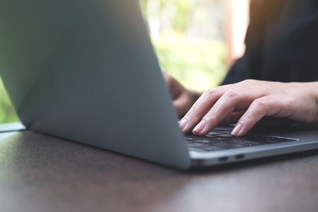 Closeup image of hands working and typing on laptop keyboard in officeの写真素材