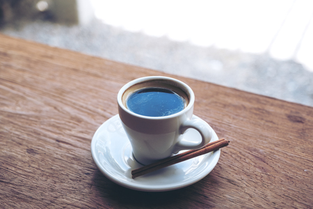 Closeup image of a white cup of hot coffee on vintage wooden tableの写真素材
