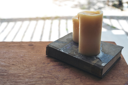 Book and candles on wooden table in cafeの写真素材