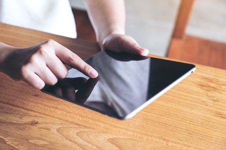 Closeup image of hands holding , using and touching a tablet pc in modern cafeの写真素材