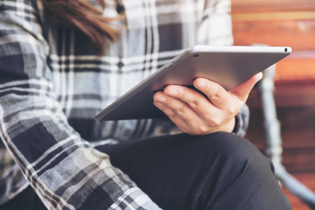 Closeup image of a woman holding and using tablet pc