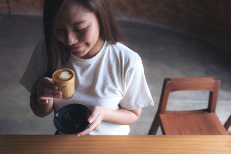 Closeup image of an Asian woman holding a coffee cup before drinking with feeling good in cafeの写真素材