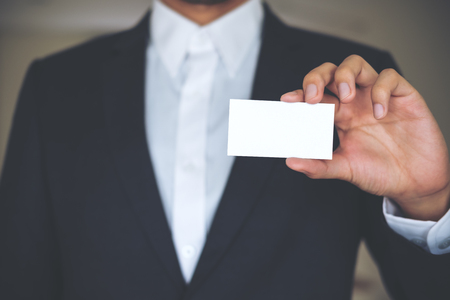 A business man in white shirt and gray suit holding and showing empty business cardの写真素材