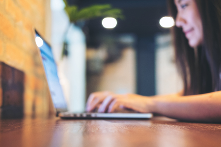 Blur image of a beautiful Asian woman using and looking at laptop in modern loft cafe