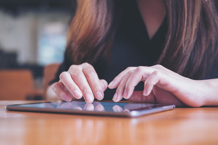 A woman's hand touching and typing on tablet pc with blur background in cafeの写真素材