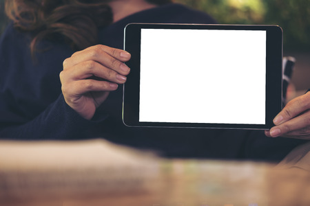 Mockup image of a woman holding and showing black tablet with blank white screen in cafeの写真素材