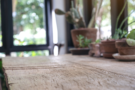 Closeup blur image of a wooden table with flowerpots in backgroundの写真素材