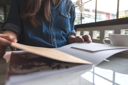 Closeup image of a woman open a book with coffee cup on table in modern cafeの写真素材