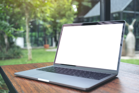 Mockup image of laptop with blank white desktop screen on vintage wooden table with nature backgroundの写真素材