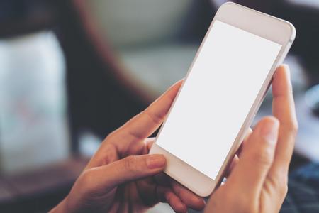 Mockup image of hand holding mobile phone with blank white screen in vintage cafeの写真素材