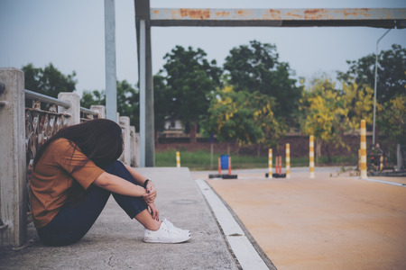 A woman sitting on the bridge with feeling sad and lonelyの写真素材