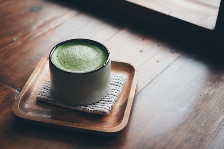 A cup of hot matcha latte on wooden floor