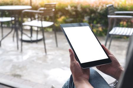 Mockup image of woman's hands holding black tablet pc with white blank desktop screen in cafeの写真素材