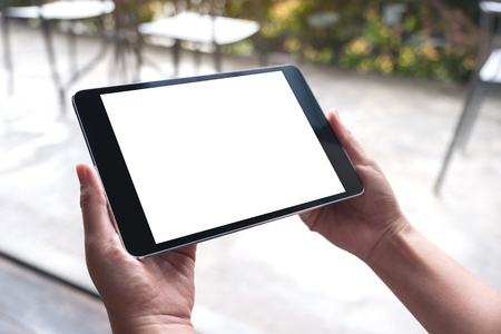Mockup image of woman's hands holding black tablet pc with white blank desktop screen in cafeの写真素材