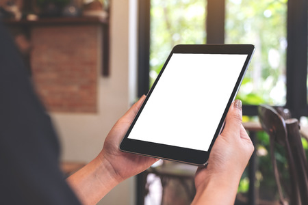 Mockup image of woman's hands holding black tablet pc with blank desktop screen in cafeの写真素材