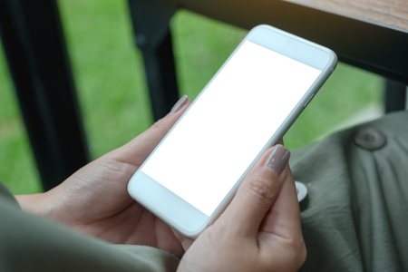 Mockup image of a woman holding white smart phone with blank desktop screen with green nature backgroundの写真素材
