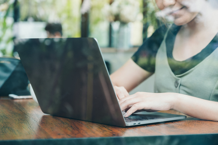 Closeup image of an asian business woman working and using laptop on wooden table in office with green nature backgroundの写真素材