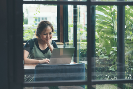 Closeup image of an asian business woman working and using laptop on wooden table in office with...