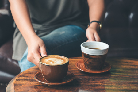Closeup image of a woman holding and serving two coffee cup in the cafeの写真素材