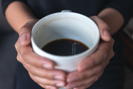 Closeup image of a woman's hands holding a white cup of hot coffeeの写真素材