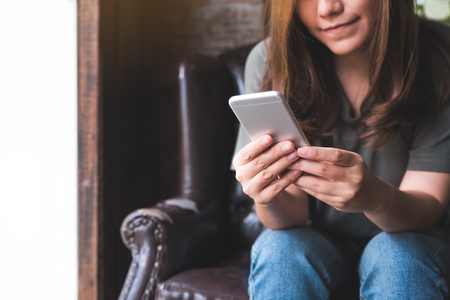 Closeup image of a beautiful asian woman holding , using and touching a smart phoneの写真素材