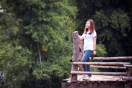 A beautiful asian woman standing on wooden balcony in front of a house with green nature backgroundの写真素材