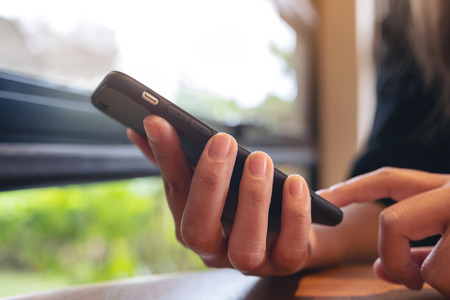 Closeup image of a woman holding , using and pointing at smart phone