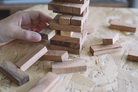 Closeup image of a hand holding and playing Tumble tower wooden block gameの写真素材