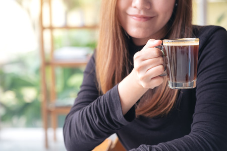 Closeup image of Asian woman smelling and drinking hot coffee with feeling good in cafeの写真素材