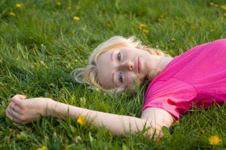 blonde girl resting on the green grassの写真素材