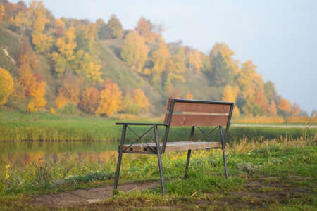 Bench  with view to autumn forest and lake .の写真素材