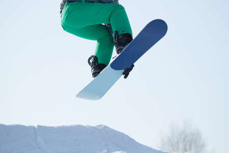 Snowboarder jumping against blue skyの写真素材