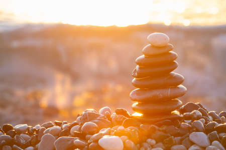 Stack of sea pebbles on a background of sunrise over the seaの写真素材