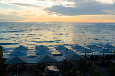 Beach umbrellas loungers on the sea at sunriseの写真素材