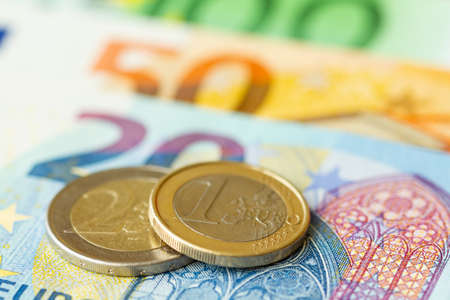 One and two Euro coins on the background of banknotesの写真素材
