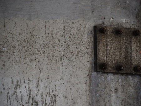 Rusty metal plate with rivets on the background of gray concrete wallの写真素材
