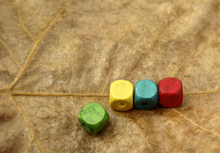 Wooden dice in various colors on a sheet of brownの写真素材
