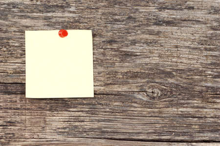 Yellow note stuck on background of wood crackedの写真素材