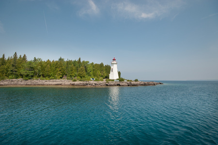 Lighthouse on a Rocky Beach with Blue Water and skyの写真素材