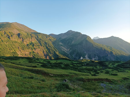Mountain landscape with green meadows and high peaks under blue sky, Kamchatka, Russia.の写真素材