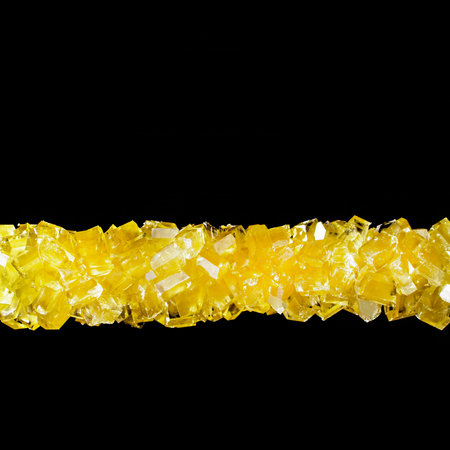 Crystallized sugar, bright yellow-orange crystals on a black background, refined product