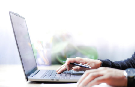 a businessman keeping records on a laptop for a business, doing accounting on a laptop, doing business online, doing business from home, hand typing on laptopの写真素材