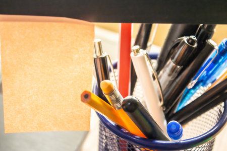 There is a blank sticker for text hanging on the monitor, and pens and pencils are lying nearby, a...