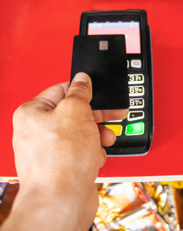 A man pays in a store with a bank card through a contactless terminalの写真素材