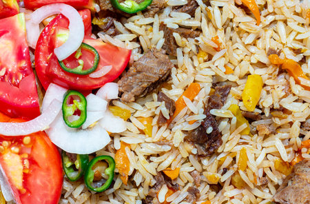 A rice dish with meat, garnished with a salad of chopped tomatoes, onions and hot green chili...