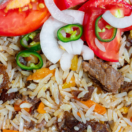 A close-up of pilaf garnished with a salad of chopped tomatoes, onions, and green chili peppers. This photo can be used in any food-themed designの写真素材